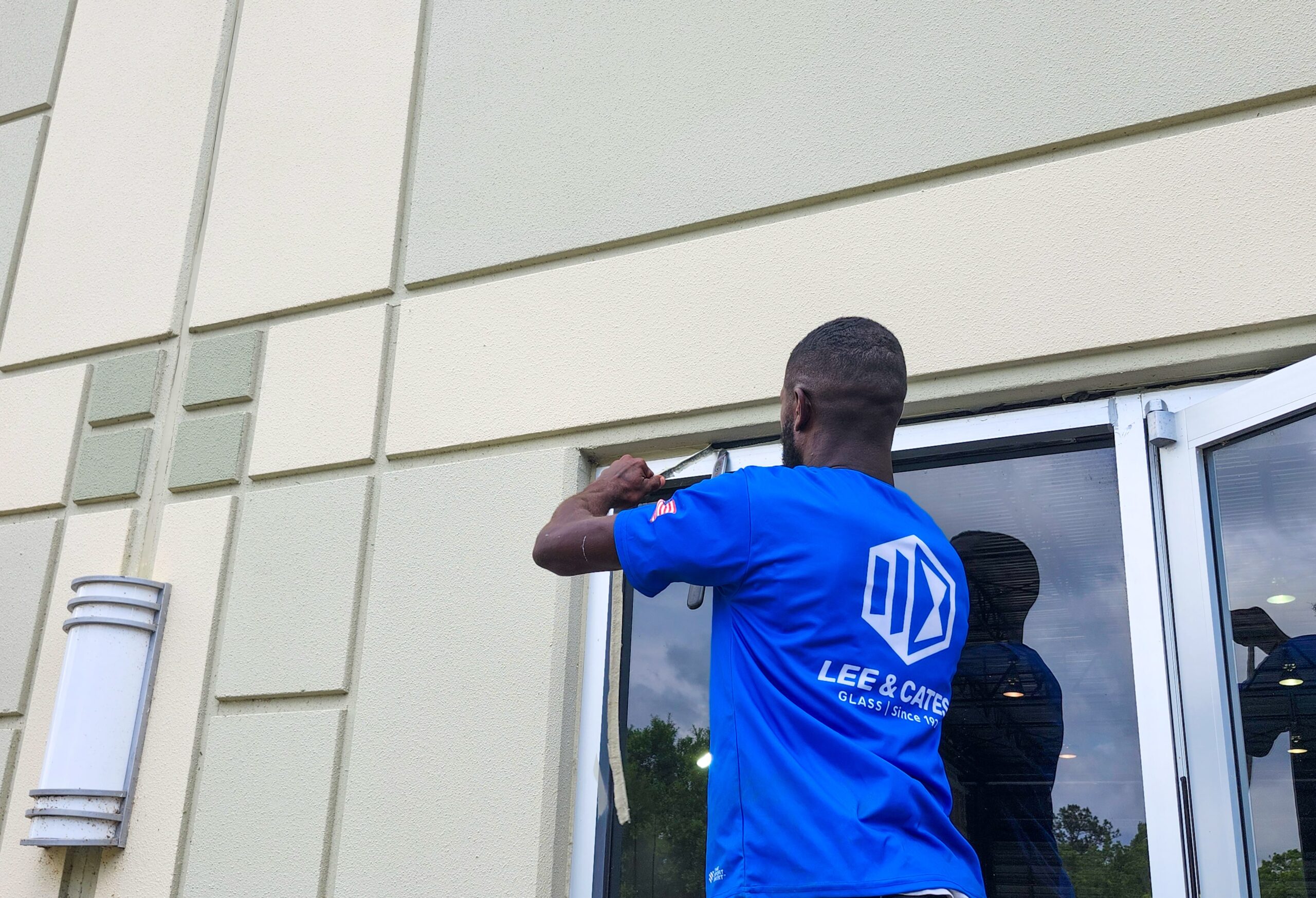 Technician applying waterproofing sealant to exterior commercial windows in Jacksonville, FL