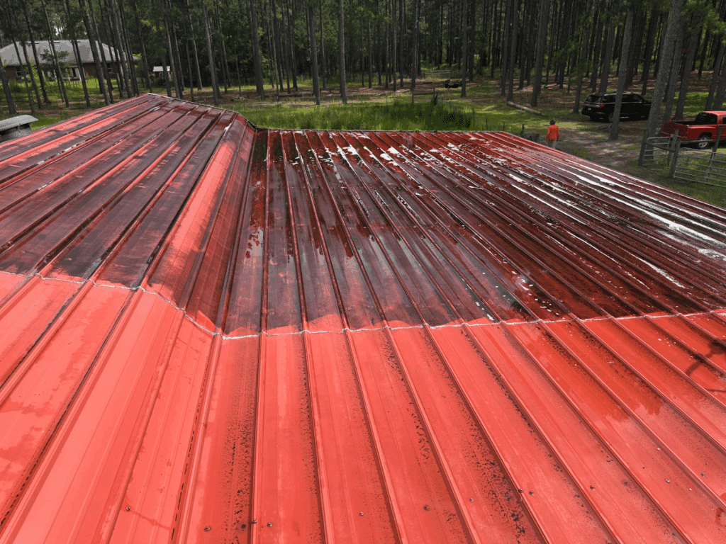Half-clean red metal roof showing dramatic before and after results from roof cleaning