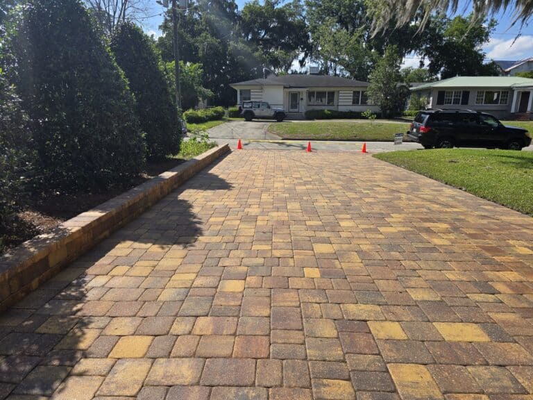 Freshly cleaned and sealed paver driveway in Jacksonville, FL with safety cones.