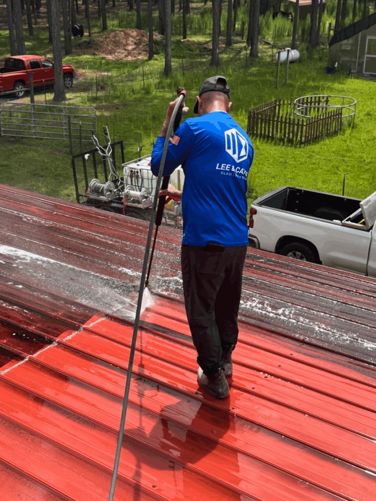Technician using soft wash system to clean red metal roof panels in Jacksonville, Florida