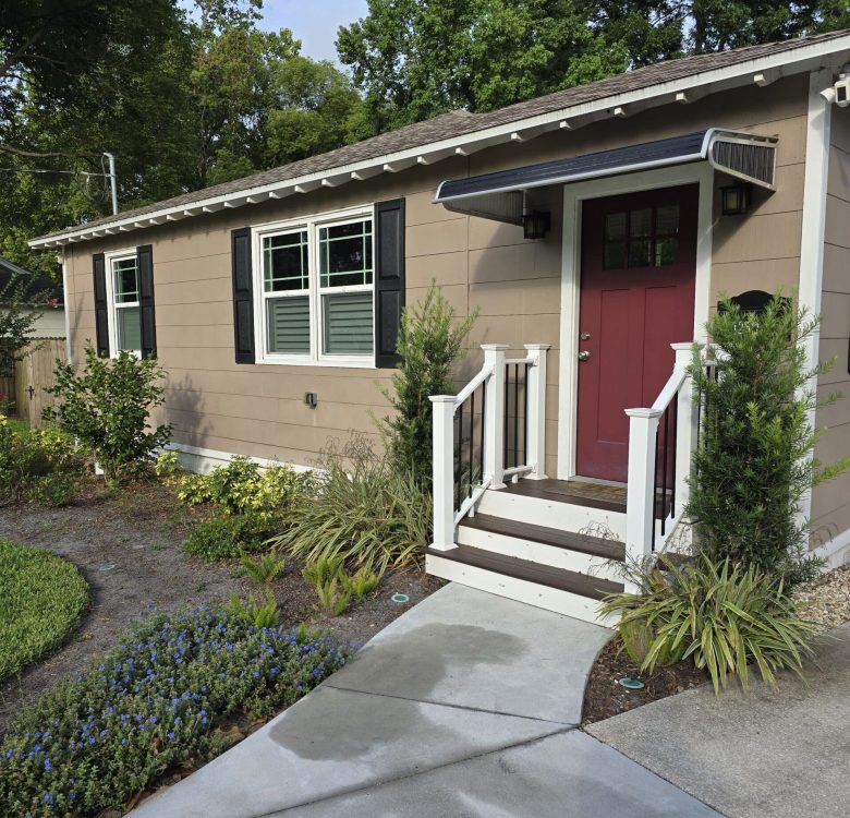 Clean concrete sidewalk and front entryway of a small Jacksonville home after professional pressure washing, showing clear contrast between washed and unwashed areas.